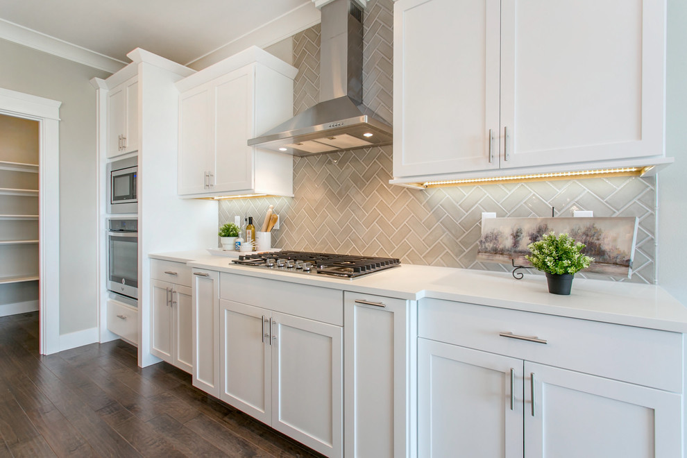 Example of a large transitional l-shaped dark wood floor open concept kitchen design in Seattle with an undermount sink, shaker cabinets, white cabinets, quartz countertops, gray backsplash, porcelain backsplash, stainless steel appliances, an island and white countertops