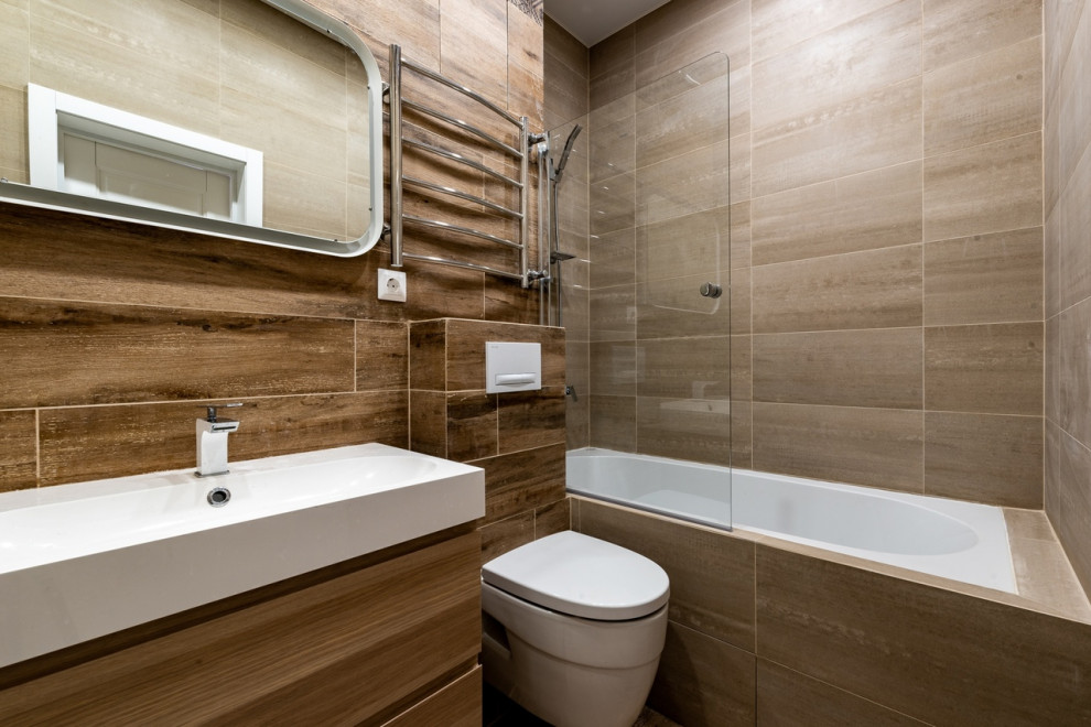 На фото: большая главная ванная комната в современном стиле с стеклянными фасадами, ванной в нише, душем над ванной, инсталляцией, монолитной раковиной, тумбой под одну раковину и встроенной тумбой с