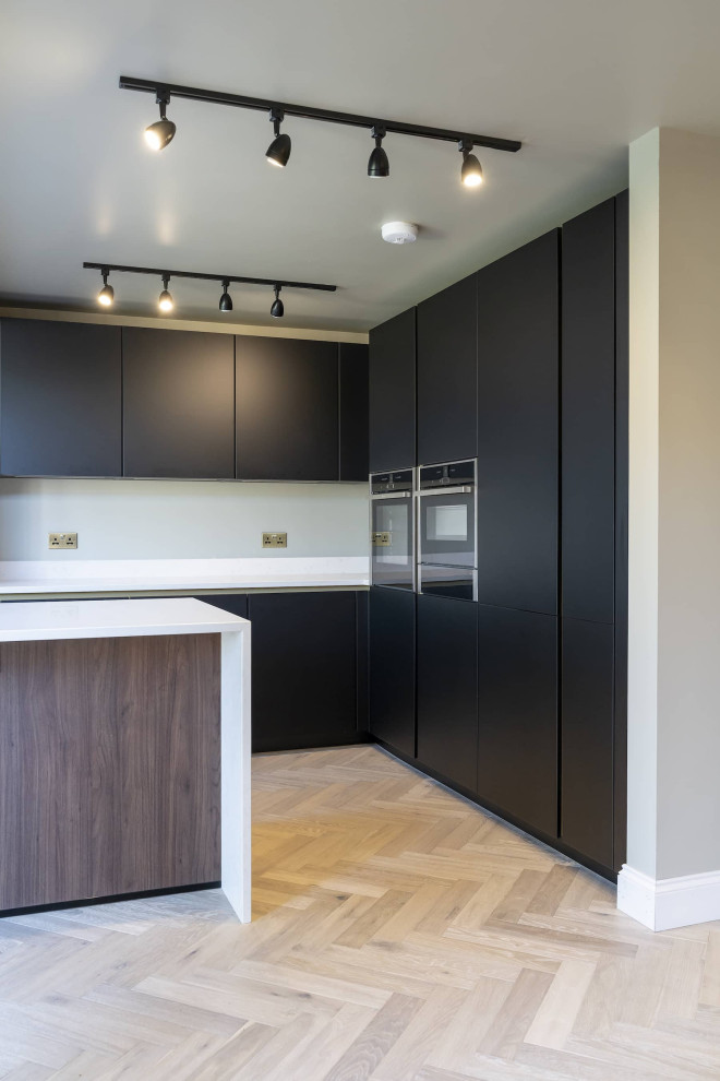 Design ideas for a small scandinavian galley open plan kitchen in Oxfordshire with an undermount sink, beaded inset cabinets, black cabinets, quartzite benchtops, white splashback, engineered quartz splashback, black appliances, with island, brown floor, white benchtop and vaulted.