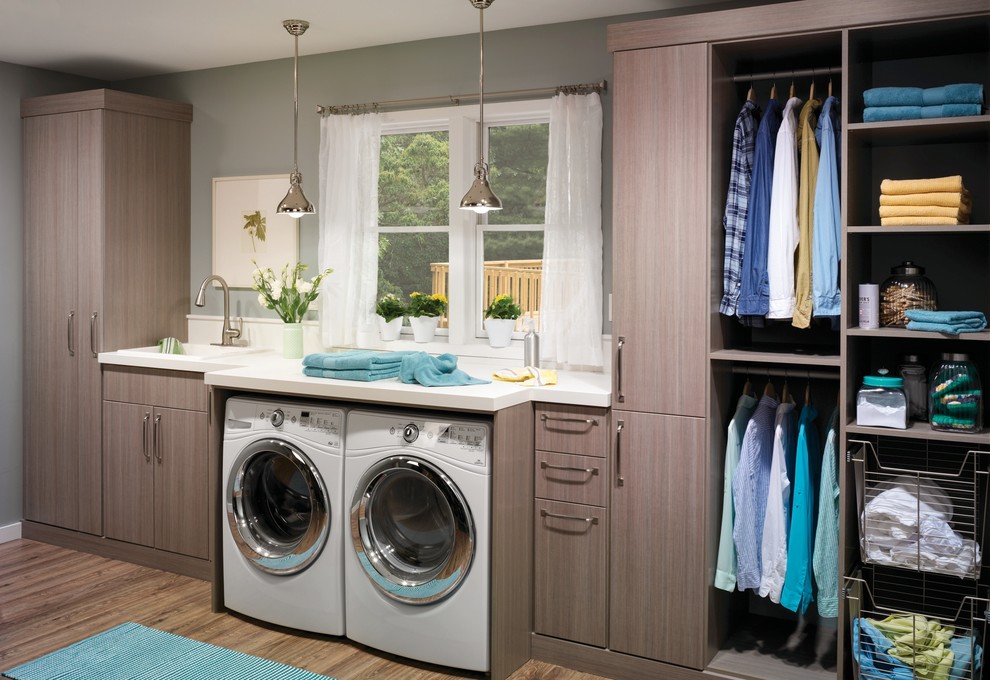 Design ideas for a large modern single-wall dedicated laundry room in Philadelphia with a single-bowl sink, flat-panel cabinets, a side-by-side washer and dryer, quartz benchtops, grey walls, medium hardwood floors and grey cabinets.