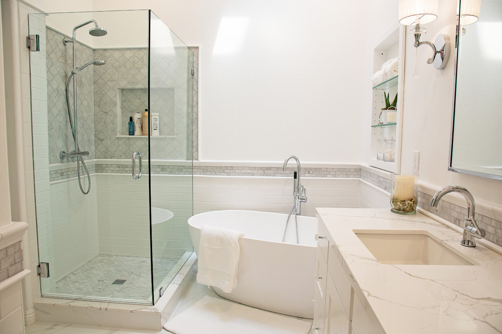 Photo of a mid-sized transitional master bathroom in Los Angeles with shaker cabinets, white cabinets, a freestanding tub, a corner shower, a two-piece toilet, white tile, marble, white walls, porcelain floors, an undermount sink, engineered quartz benchtops, white floor, a hinged shower door and white benchtops.