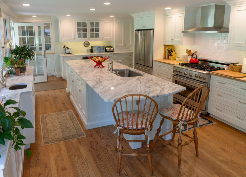 Inspiration for a large transitional medium tone wood floor and brown floor eat-in kitchen remodel with an undermount sink, flat-panel cabinets, white cabinets, quartzite countertops, white backsplash, ceramic backsplash, stainless steel appliances, an island and white countertops