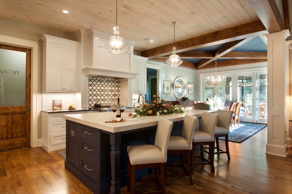 Example of a mid-sized transitional l-shaped light wood floor and brown floor eat-in kitchen design with an undermount sink, shaker cabinets, white cabinets, wood countertops, multicolored backsplash, glass tile backsplash, stainless steel appliances and an island