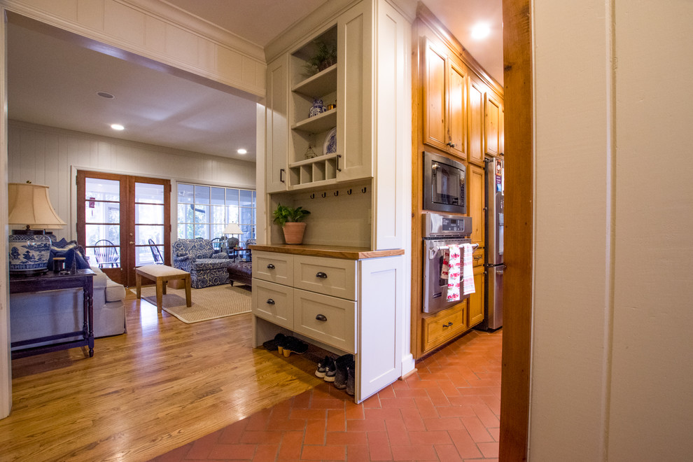 Mid-sized country separate kitchen in Atlanta with a farmhouse sink, shaker cabinets, beige cabinets, wood benchtops, white splashback, timber splashback, stainless steel appliances, brick floors, with island, orange floor and brown benchtop.