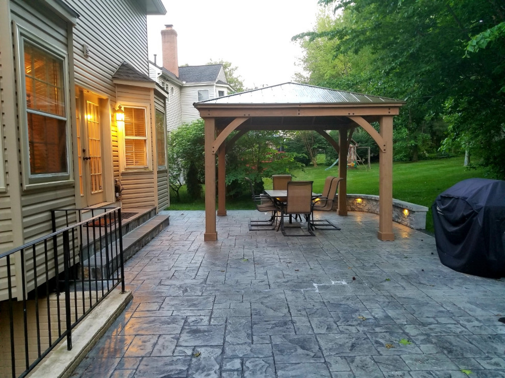 Photo of a large traditional backyard patio in DC Metro with a fire feature, stamped concrete and a gazebo/cabana.