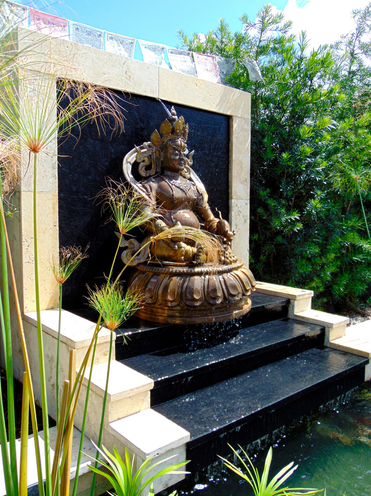 Inspiration for a small asian backyard custom-shaped natural pool in Miami with a water feature and natural stone pavers.