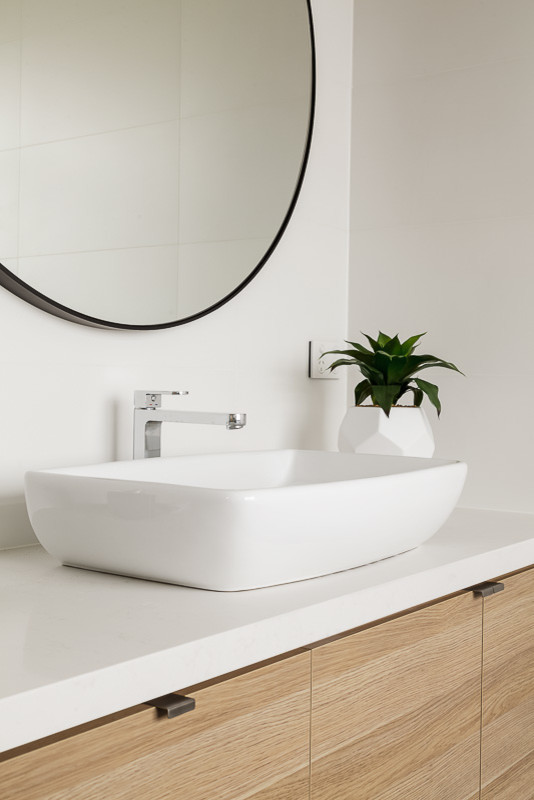 This is an example of a scandinavian master bathroom in Melbourne with flat-panel cabinets, light wood cabinets, a freestanding tub, a corner shower, white tile, white walls, porcelain floors, a vessel sink, engineered quartz benchtops, grey floor and a hinged shower door.