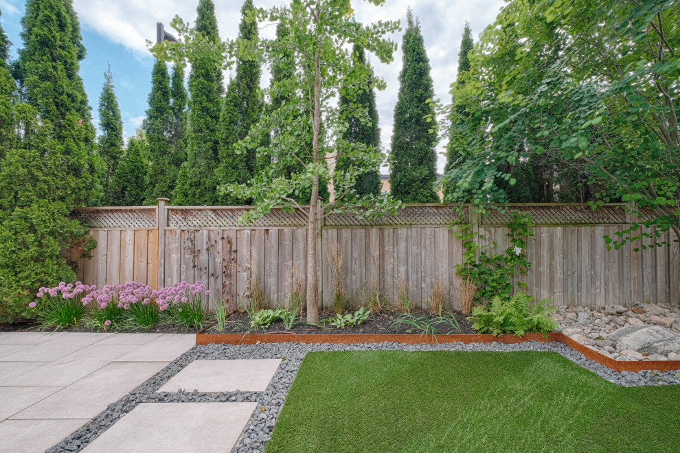 Идея дизайна: летний участок и сад среднего размера на заднем дворе в современном стиле с клумбами, полуденной тенью, покрытием из каменной брусчатки и с деревянным забором