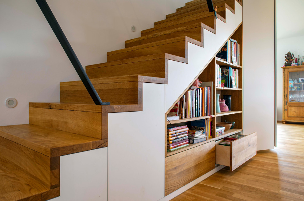 Ejemplo de escalera recta escandinava con escalones de madera, contrahuellas de madera y barandilla de metal