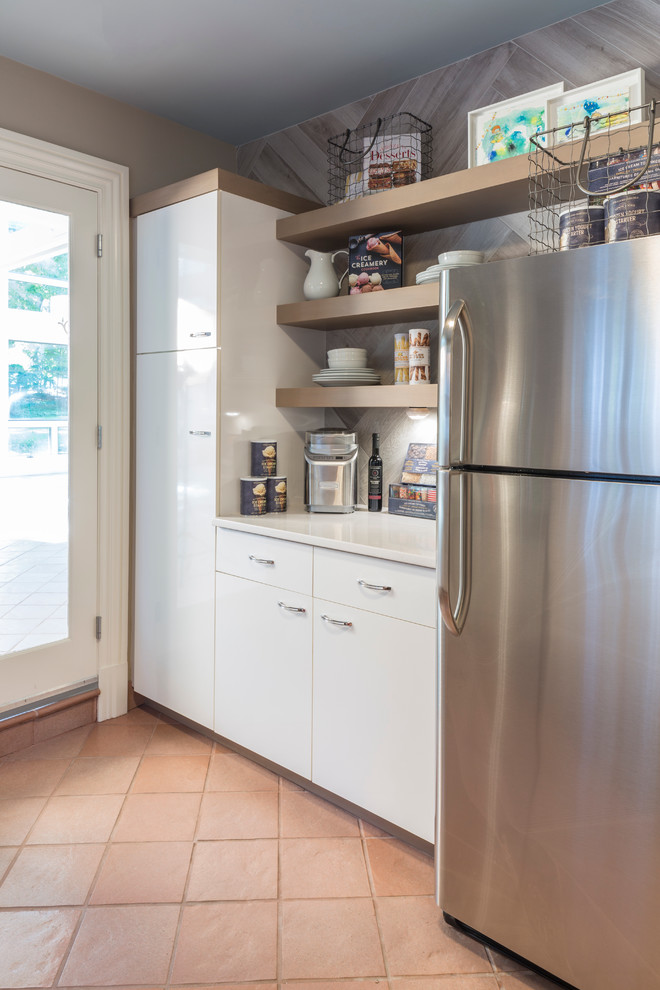 Inspiration for a mid-sized beach style galley separate kitchen in New York with an undermount sink, flat-panel cabinets, white cabinets, quartz benchtops, grey splashback, porcelain splashback, stainless steel appliances and terra-cotta floors.