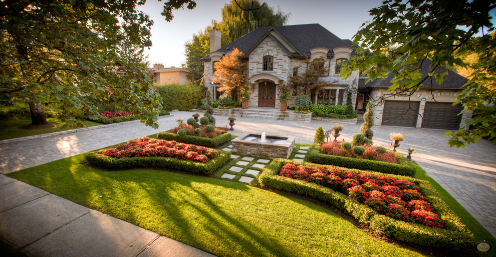 Large traditional front yard full sun formal garden in Toronto with a water feature and brick pavers for summer.