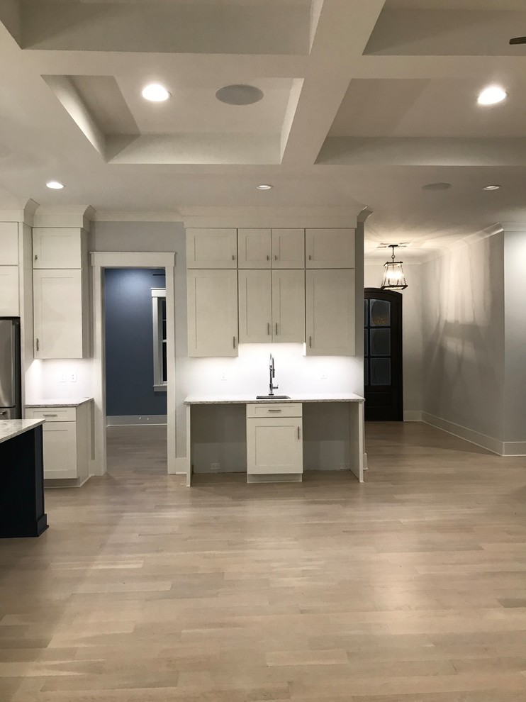 Example of a mid-sized transitional l-shaped light wood floor and beige floor open concept kitchen design in Cincinnati with an undermount sink, shaker cabinets, white cabinets, granite countertops, stainless steel appliances, an island and gray countertops