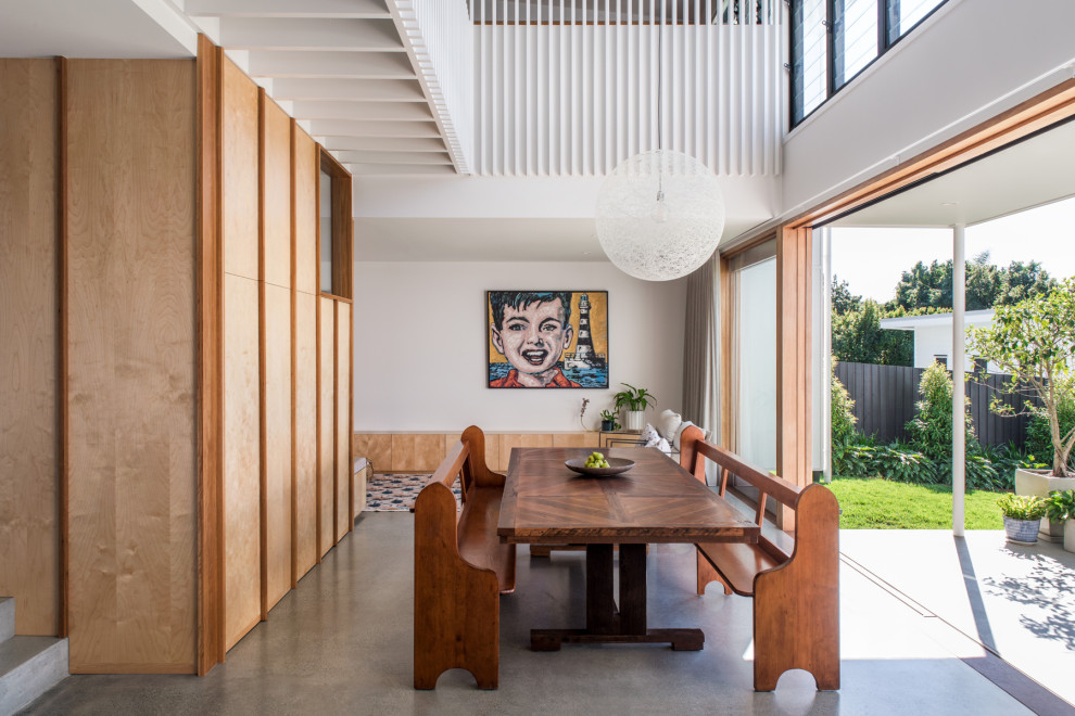 This is an example of a large contemporary dining room in Brisbane with white walls and concrete floors.