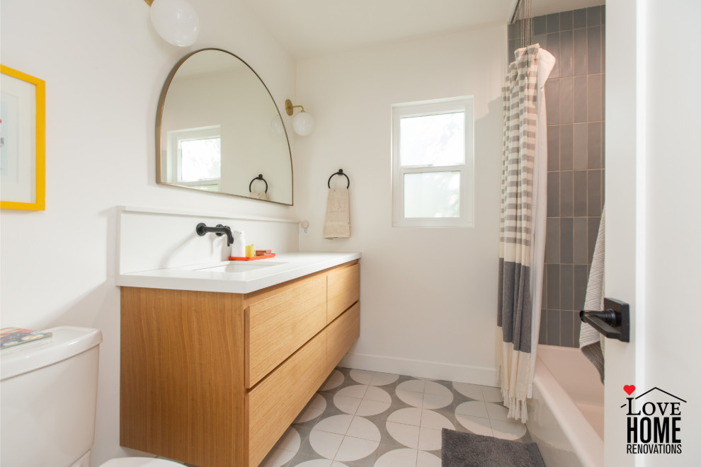Идея дизайна: маленькая детская ванная комната в стиле ретро с плоскими фасадами, светлыми деревянными фасадами, ванной в нише, душем над ванной, унитазом-моноблоком, синей плиткой, керамической плиткой, белыми стенами, полом из цементной плитки, врезной раковиной, столешницей из искусственного кварца, серым полом, шторкой для ванной, белой столешницей, нишей, тумбой под одну раковину и подвесной тумбой для на участке и в саду
