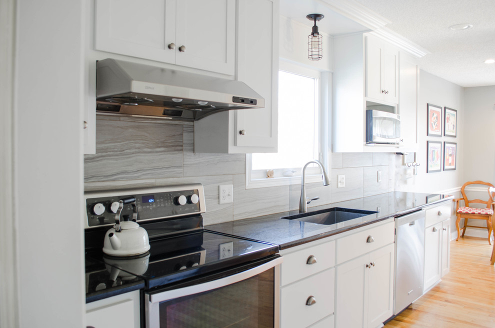 Inspiration for a small transitional galley eat-in kitchen in Kansas City with a double-bowl sink, shaker cabinets, white cabinets, granite benchtops, grey splashback, ceramic splashback, stainless steel appliances, medium hardwood floors and no island.