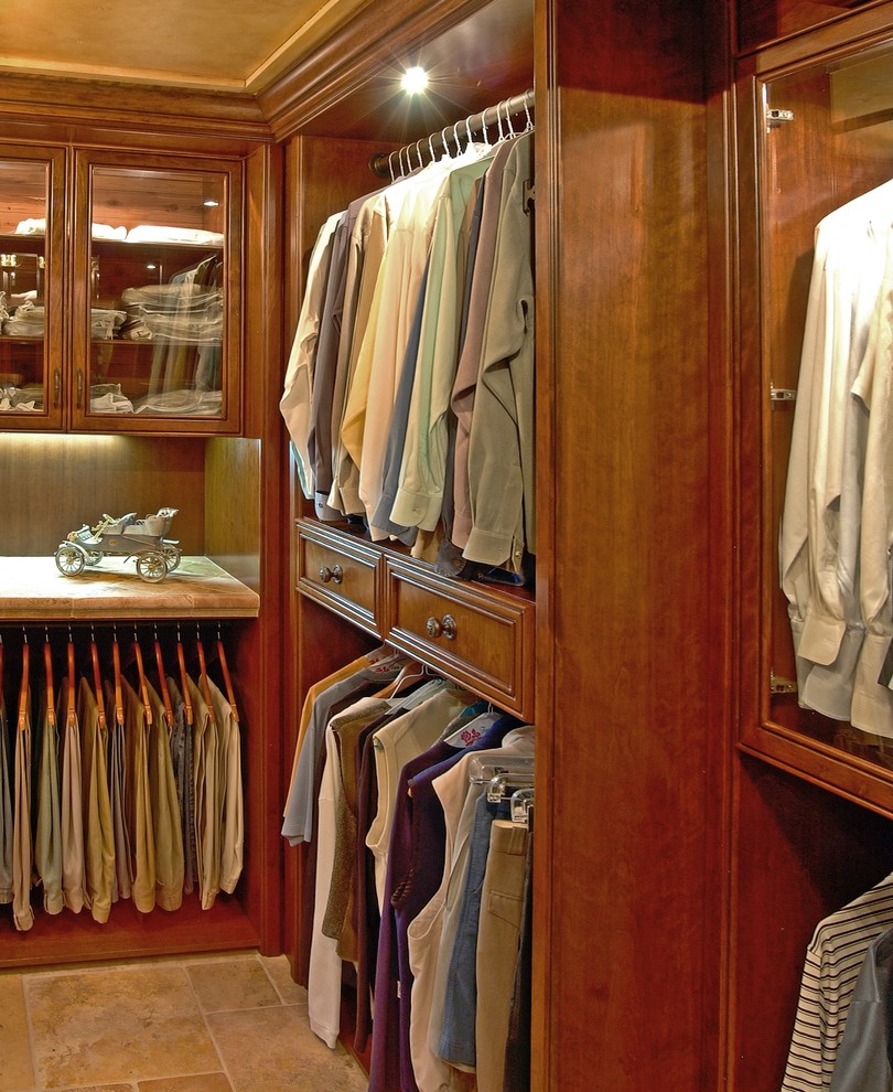 Photo of a mid-sized traditional gender-neutral walk-in wardrobe in Other with recessed-panel cabinets, medium wood cabinets and travertine floors.