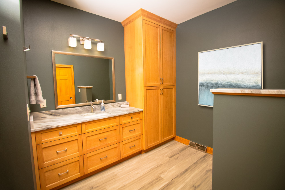 This is an example of a transitional master bathroom in Milwaukee with shaker cabinets, light wood cabinets, an alcove shower, a bidet, gray tile, porcelain tile, green walls, vinyl floors, an undermount sink, granite benchtops, a hinged shower door, multi-coloured benchtops, a shower seat, a double vanity and a built-in vanity.