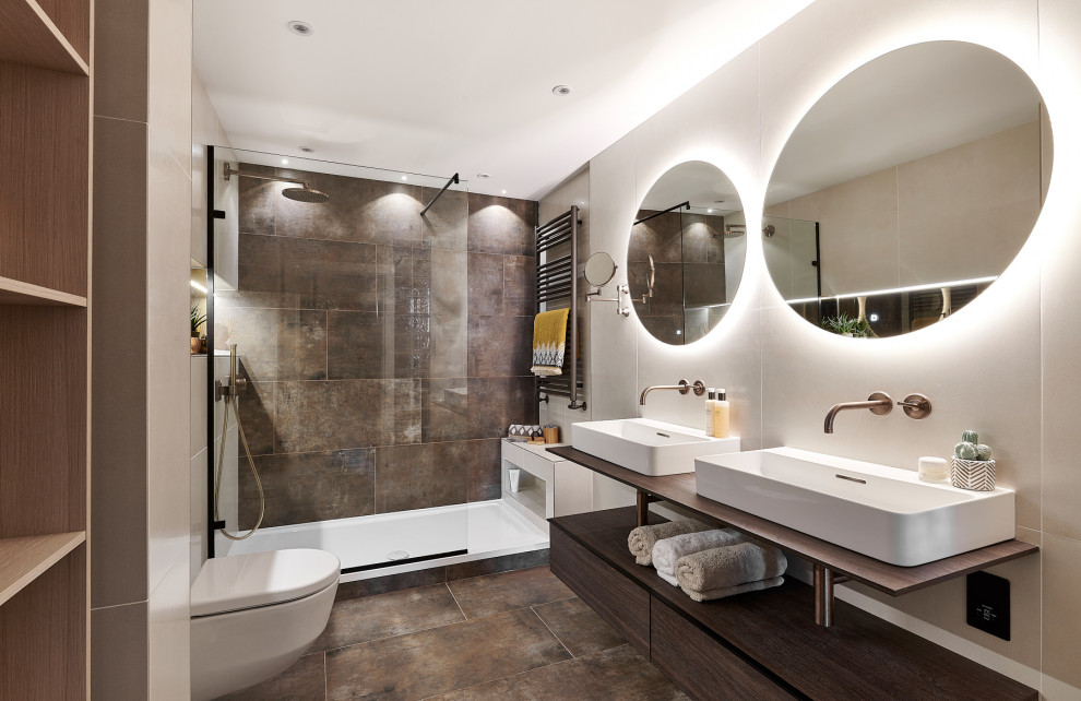 This is an example of a mid-sized contemporary master bathroom in Cardiff with open cabinets, dark wood cabinets, an open shower, a wall-mount toilet, brown tile, porcelain tile, beige walls, porcelain floors, brown floor, an open shower and a double vanity.