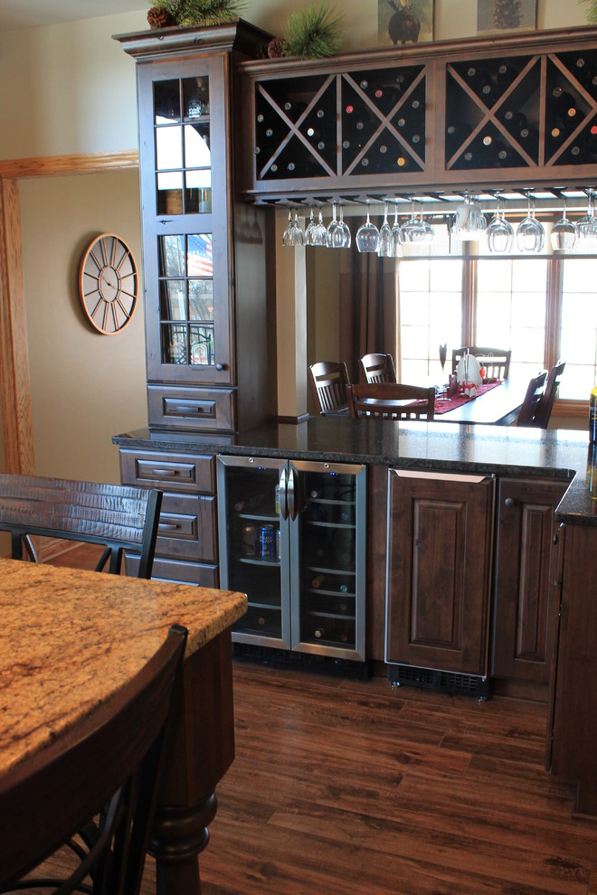 Inspiration for a mid-sized rustic u-shaped medium tone wood floor eat-in kitchen remodel with raised-panel cabinets, dark wood cabinets, granite countertops, a double-bowl sink, beige backsplash, an island, ceramic backsplash and black appliances