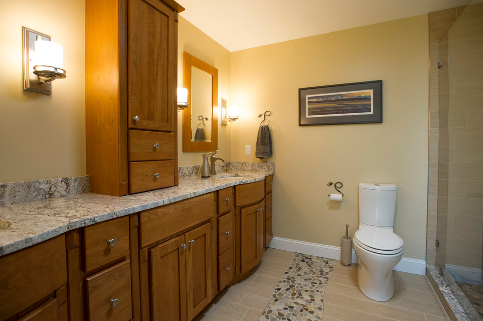 Photo of a mid-sized arts and crafts master bathroom in Boston with an undermount sink, shaker cabinets, medium wood cabinets, granite benchtops, a corner shower, a one-piece toilet, beige tile, ceramic tile, yellow walls and porcelain floors.