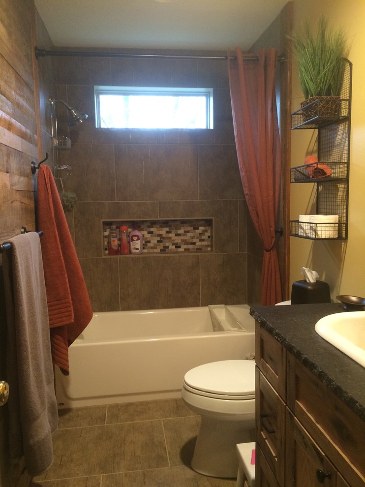 Inspiration for a mid-sized country kids bathroom in Kansas City with a wall-mount sink, shaker cabinets, medium wood cabinets, granite benchtops, an alcove tub, a shower/bathtub combo, a two-piece toilet, brown tile, porcelain tile, beige walls and porcelain floors.