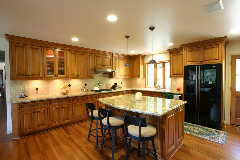 This is an example of a traditional l-shaped eat-in kitchen in San Francisco with an undermount sink, raised-panel cabinets, medium wood cabinets, granite benchtops and black appliances.