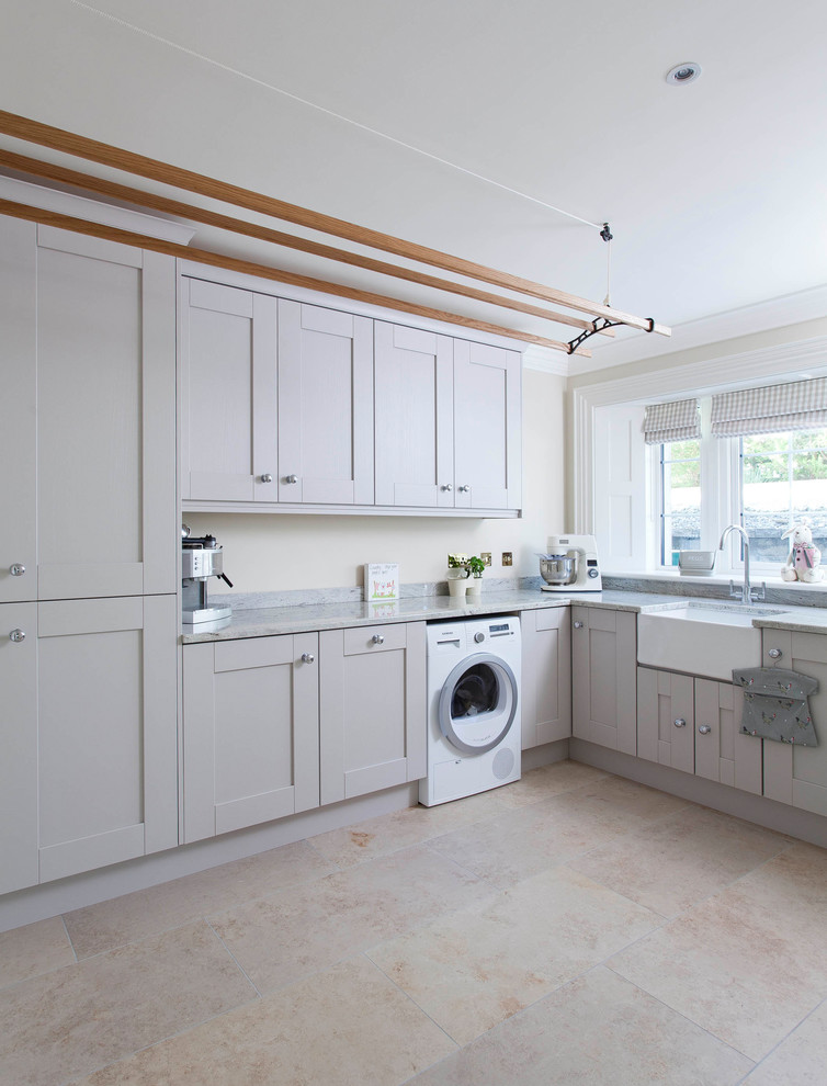 Design ideas for a large country l-shaped laundry room in Belfast with an undermount sink, beaded inset cabinets, blue cabinets, quartzite benchtops, white splashback, ceramic splashback, ceramic floors and grey floor.