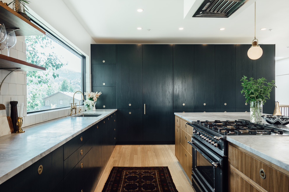 This is an example of a large eclectic l-shaped open plan kitchen in Salt Lake City with a drop-in sink, flat-panel cabinets, green cabinets, marble benchtops, white splashback, ceramic splashback, coloured appliances, light hardwood floors and with island.