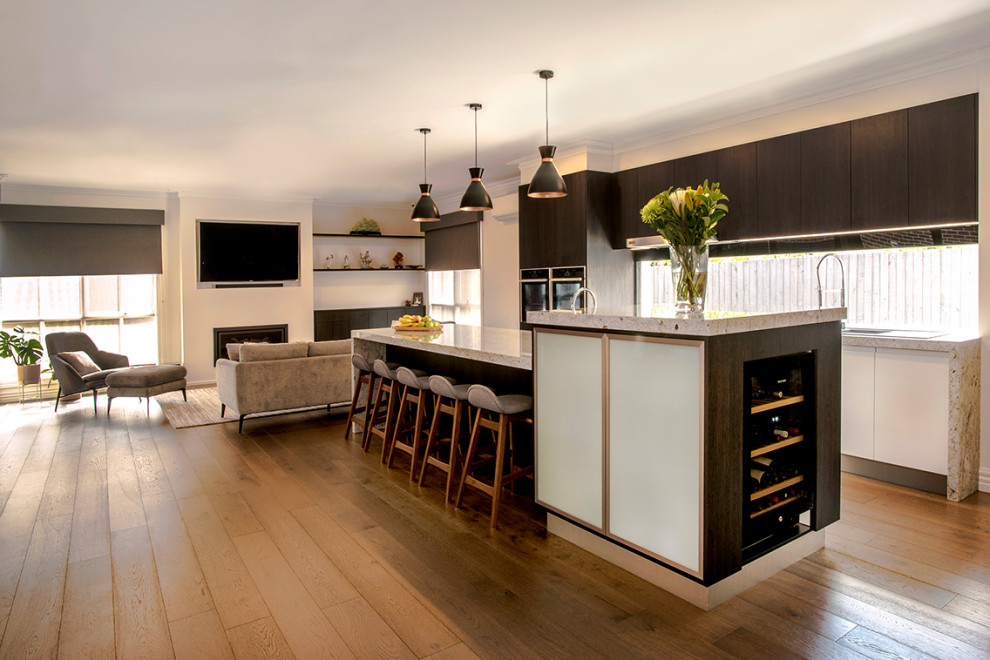Photo of a large contemporary galley open plan kitchen in Melbourne with a double-bowl sink, flat-panel cabinets, dark wood cabinets, granite benchtops, window splashback, stainless steel appliances, medium hardwood floors, with island, brown floor and multi-coloured benchtop.