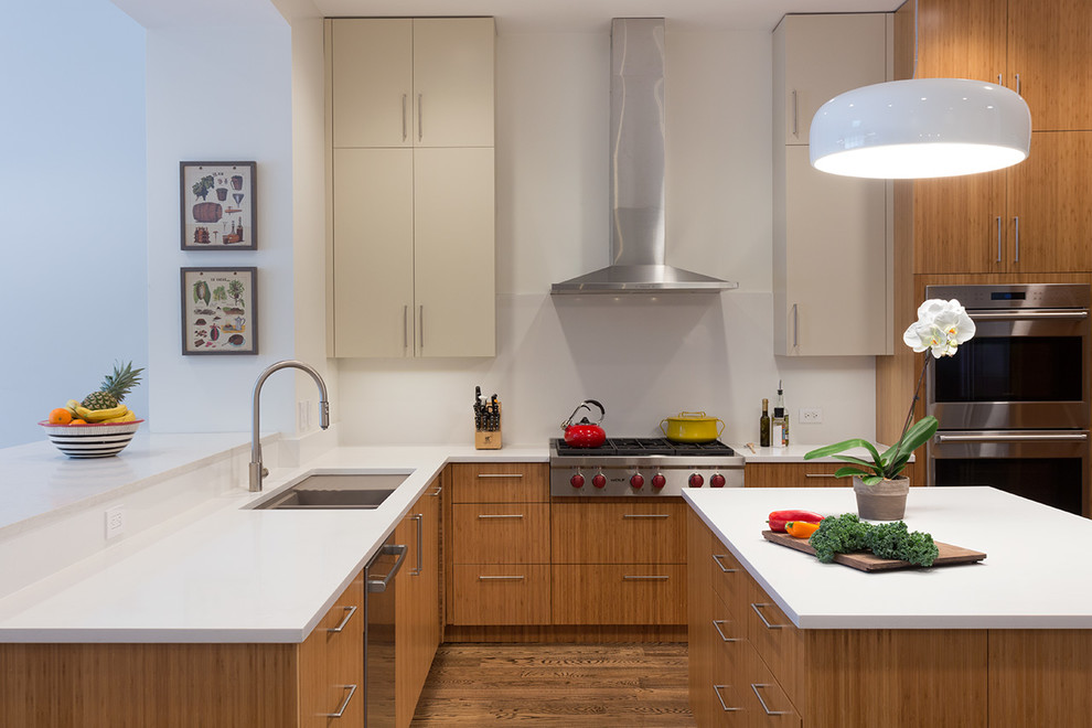 This is an example of a mid-sized contemporary l-shaped eat-in kitchen in New York with an undermount sink, flat-panel cabinets, medium wood cabinets, quartz benchtops, white splashback, stainless steel appliances, medium hardwood floors and with island.