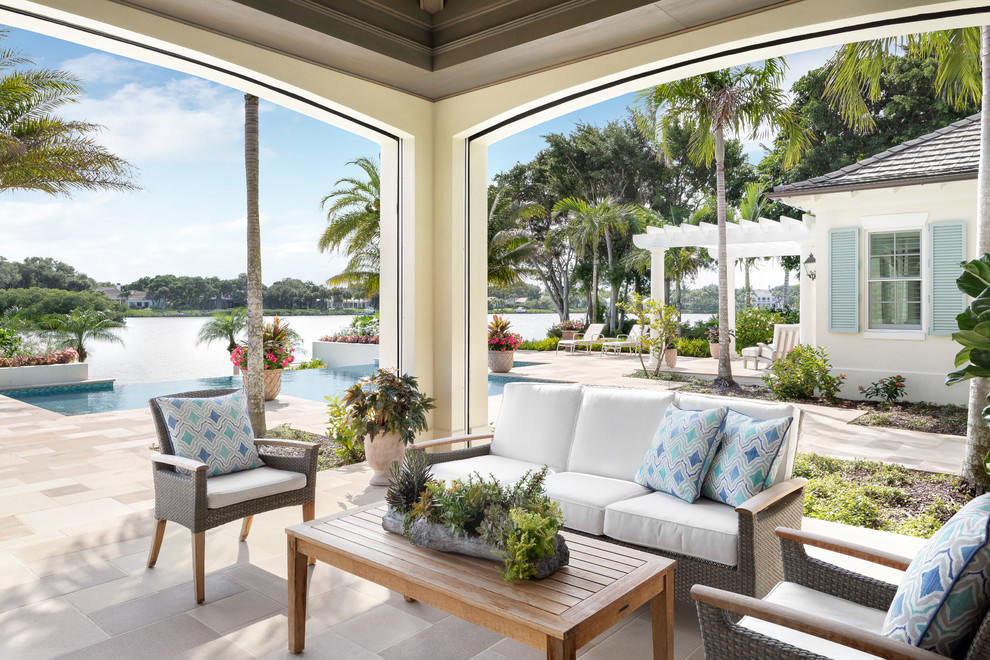 Photo of an expansive beach style backyard patio in Miami with tile and a roof extension.
