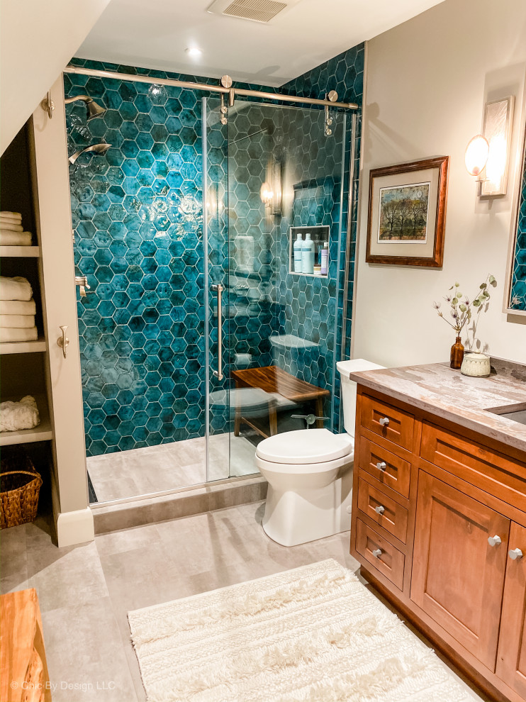 Example of a mountain style green tile and terra-cotta tile ceramic tile and gray floor sliding shower door design with shaker cabinets, brown cabinets, a two-piece toilet, gray walls, an undermount sink, quartz countertops and gray countertops