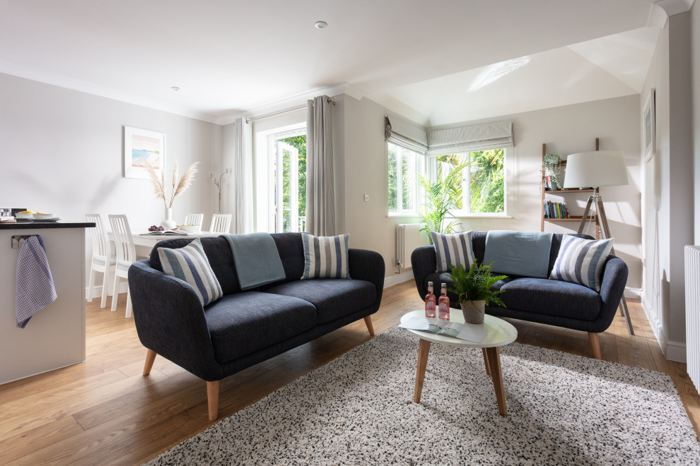 Kleines, Offenes Skandinavisches Wohnzimmer ohne Kamin mit grauer Wandfarbe, hellem Holzboden, TV-Wand und beigem Boden in Cornwall