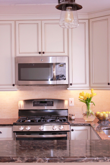 Example of a small transitional u-shaped dark wood floor enclosed kitchen design with an undermount sink, beaded inset cabinets, white cabinets, quartzite countertops, beige backsplash and stainless steel appliances