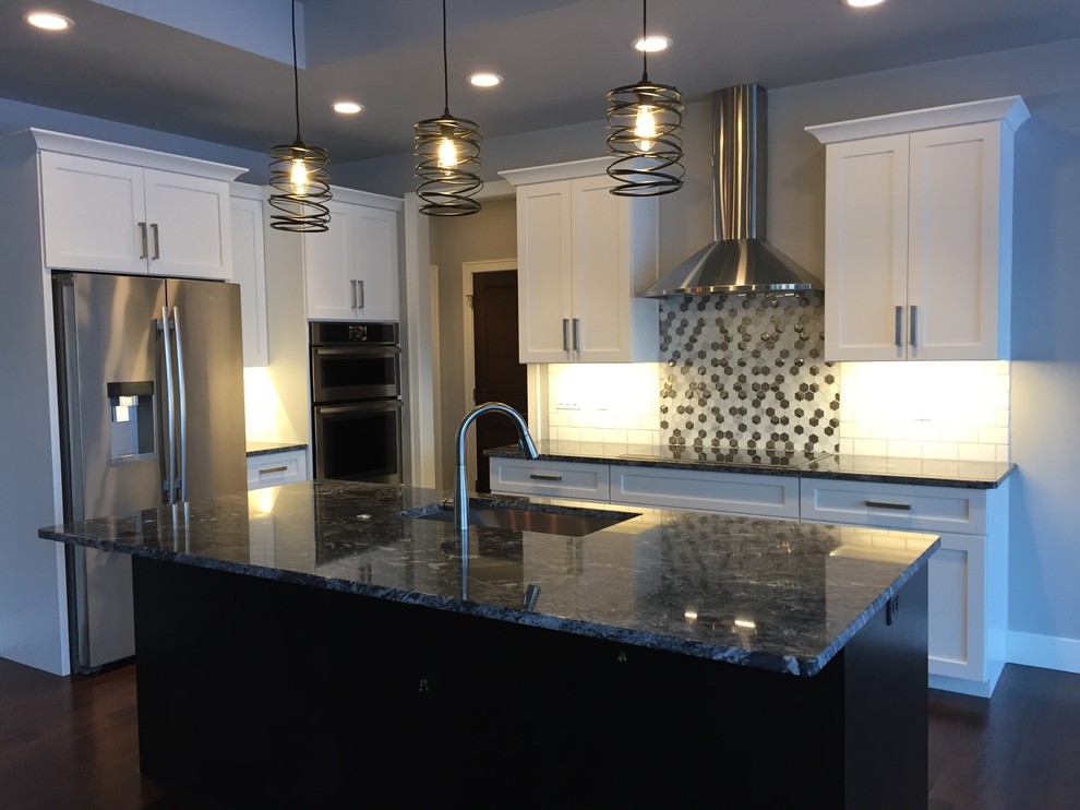Inspiration for a transitional u-shaped dark wood floor and brown floor eat-in kitchen remodel with an undermount sink, shaker cabinets, white cabinets, granite countertops, white backsplash, subway tile backsplash, stainless steel appliances and an island