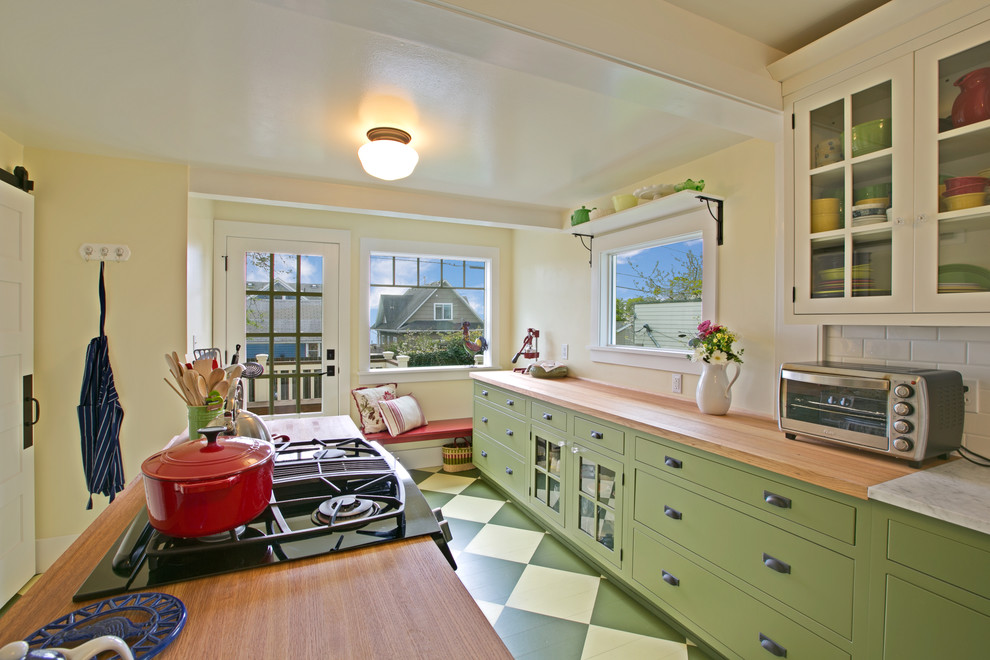 Inspiration for a craftsman u-shaped painted wood floor enclosed kitchen remodel in Seattle with glass-front cabinets, green cabinets, wood countertops, white backsplash, subway tile backsplash, stainless steel appliances and an island