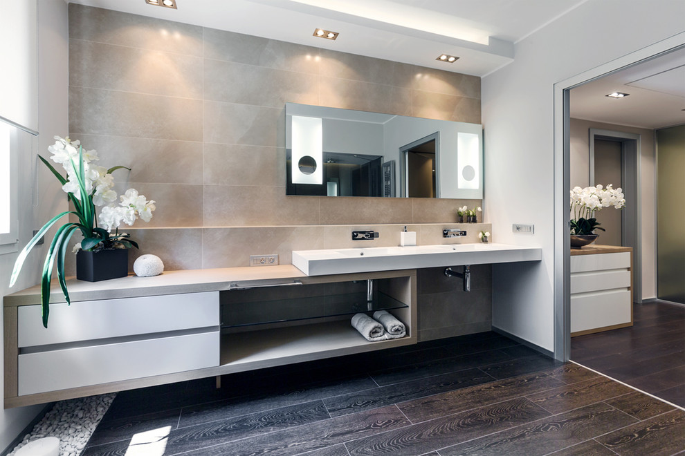 Photo of a contemporary bathroom in Other with a trough sink, open cabinets, white cabinets, beige tile, stone slab, grey walls and dark hardwood floors.