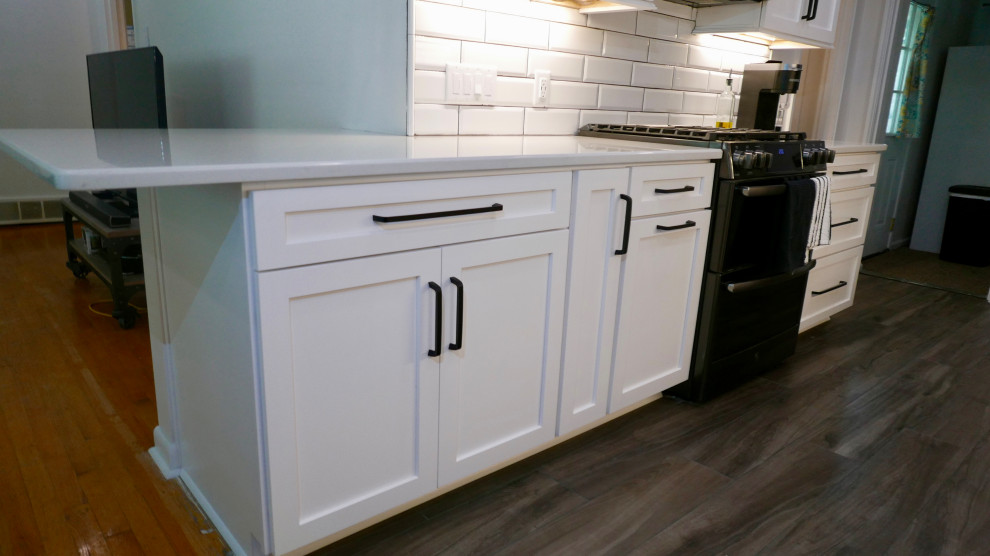 Mid-sized transitional galley porcelain tile and gray floor eat-in kitchen photo with an undermount sink, shaker cabinets, white cabinets, quartz countertops, white backsplash, subway tile backsplash, black appliances, no island and white countertops