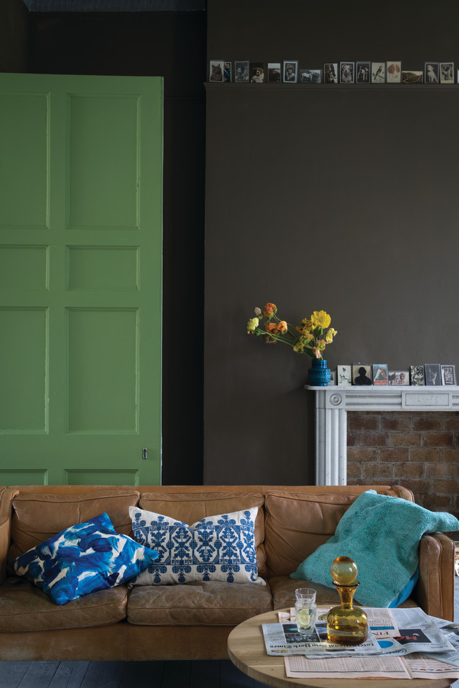 Design ideas for a transitional living room in London with black walls and a standard fireplace.