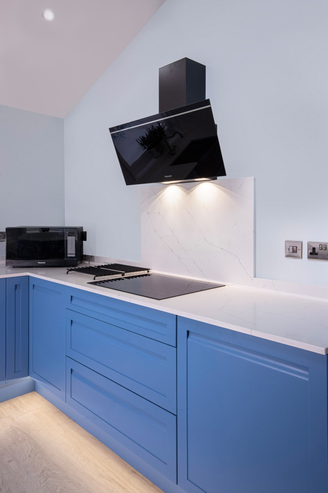 Medium sized modern kitchen in Other with a belfast sink, blue cabinets, integrated appliances, grey floors, white worktops, a vaulted ceiling and feature lighting.