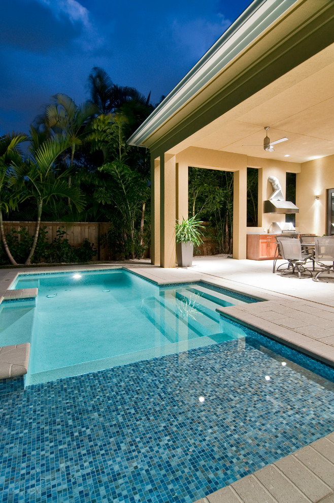 Design ideas for a small contemporary backyard custom-shaped pool in Miami with a water feature and concrete pavers.