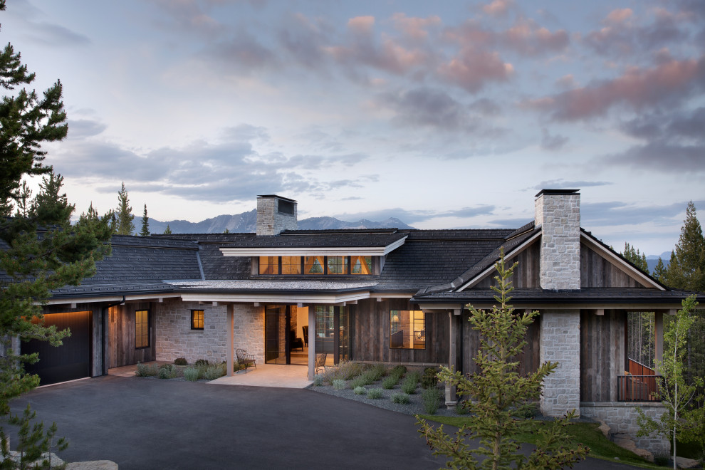 Example of a huge mountain style beige two-story stone house exterior design in Los Angeles with a shingle roof and a gray roof