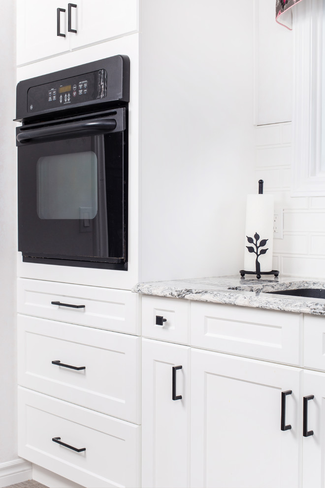 Example of a mid-sized transitional galley porcelain tile and gray floor eat-in kitchen design with a double-bowl sink, shaker cabinets, white cabinets, granite countertops, white backsplash, subway tile backsplash, stainless steel appliances, no island and gray countertops