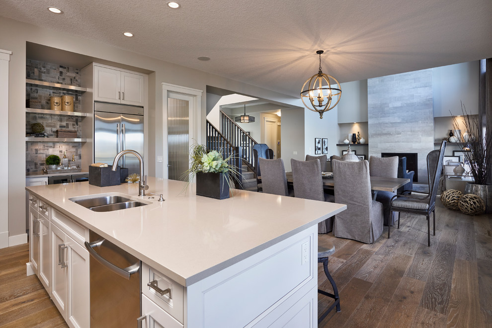 Inspiration for a mid-sized transitional l-shaped medium tone wood floor open concept kitchen remodel in Calgary with an undermount sink, recessed-panel cabinets, white cabinets, quartzite countertops, gray backsplash, ceramic backsplash, stainless steel appliances and an island