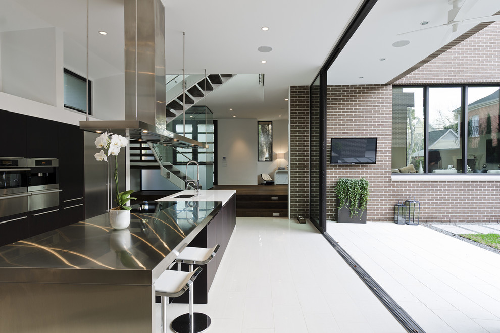 Inspiration for a contemporary galley kitchen in Houston with stainless steel benchtops, flat-panel cabinets, dark wood cabinets and stainless steel appliances.