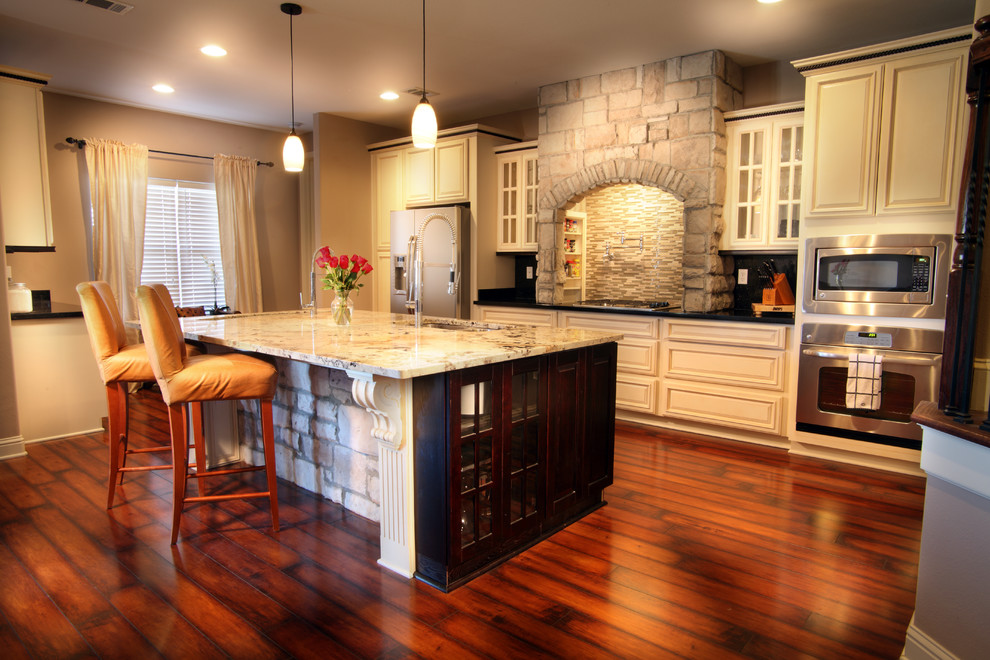 Large elegant kitchen photo in New Orleans with a drop-in sink, beaded inset cabinets, white cabinets, beige backsplash, stainless steel appliances and an island