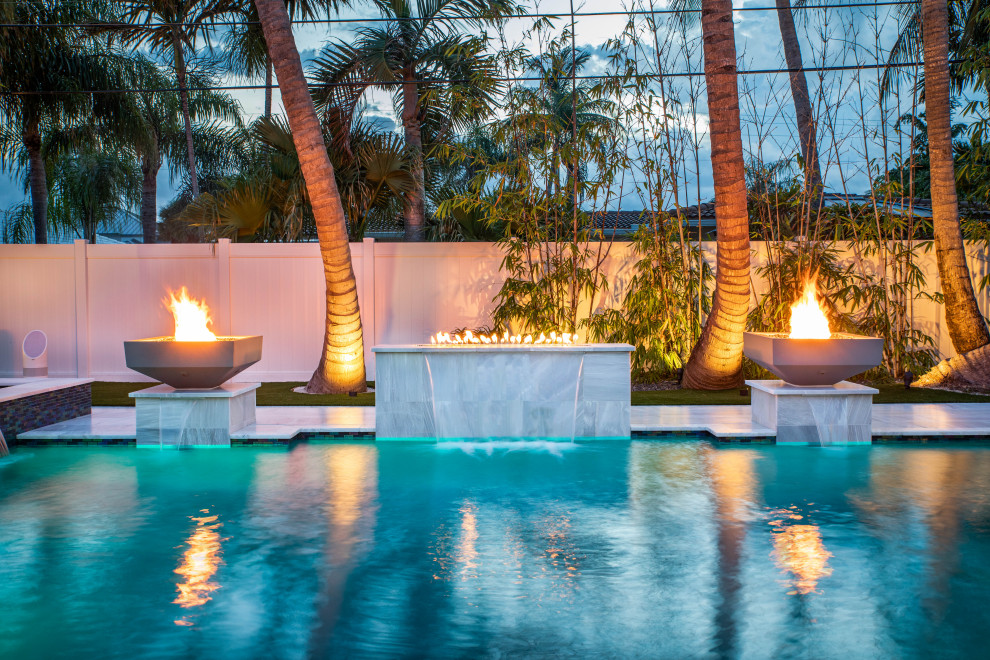 This is an example of a mid-sized modern backyard custom-shaped pool in Miami with a water feature.