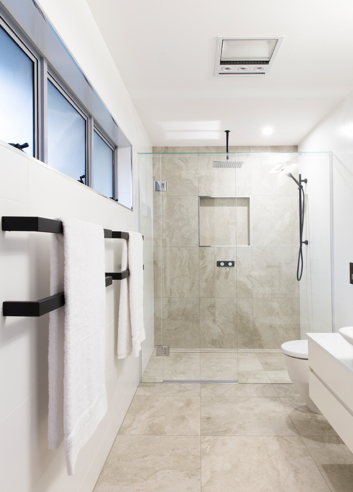 Photo of a small contemporary master bathroom in Gold Coast - Tweed with open cabinets, white cabinets, a freestanding tub, a double shower, a wall-mount toilet, beige tile, limestone, beige walls, limestone floors, a vessel sink, engineered quartz benchtops, beige floor and a hinged shower door.