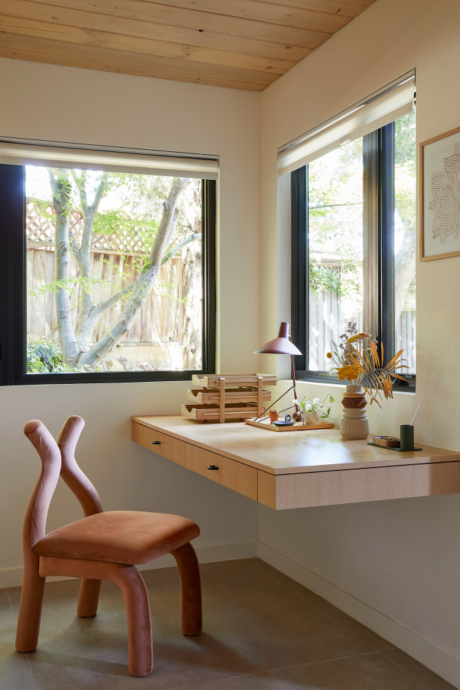 Diseño de despacho retro pequeño con paredes blancas, suelo de baldosas de porcelana, escritorio empotrado, suelo beige y madera