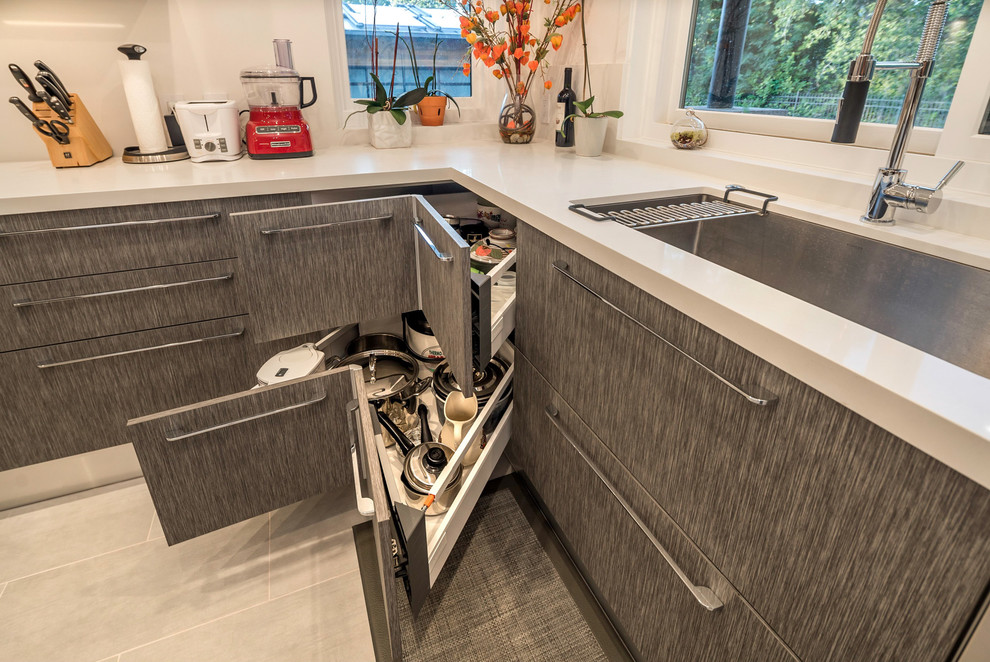 This is an example of a large contemporary u-shaped open plan kitchen in San Francisco with a drop-in sink, flat-panel cabinets, dark wood cabinets, quartz benchtops, white splashback, stainless steel appliances, with island, ceramic floors and grey floor.